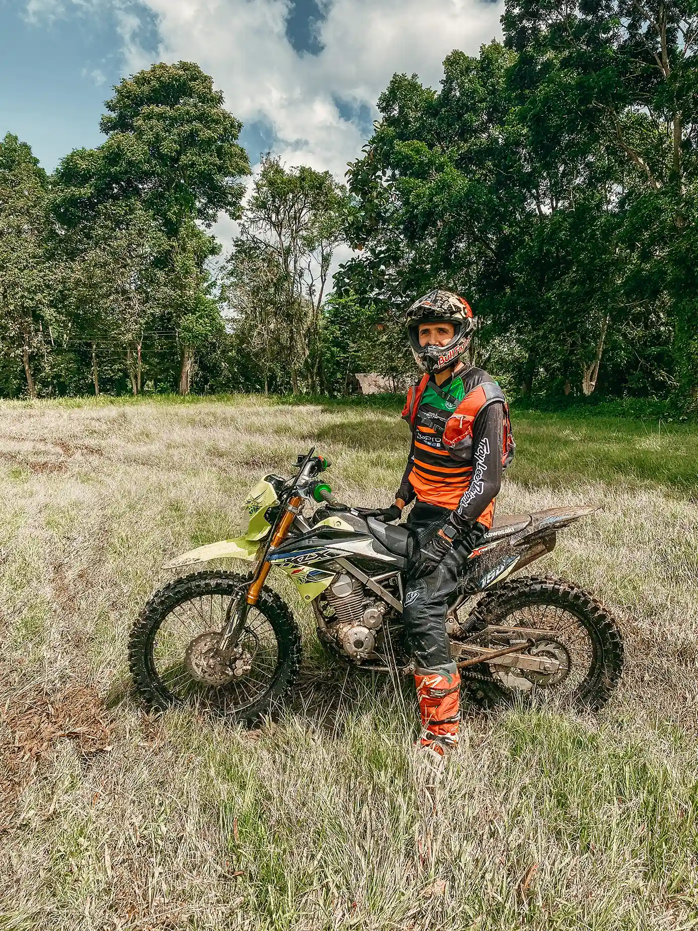 Roman standing next to a dirt bike in a field